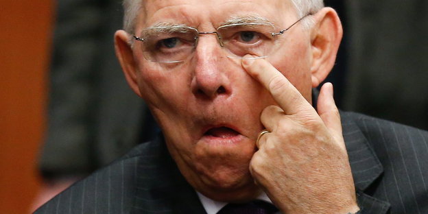 Wolfgang Schäuble hält seinen linken Zeigefinger an sein linkes Auge