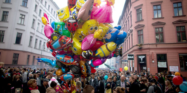 Eine Straße voller Menschen, in der Mitte ein dicker Strauß bunter Luftballons