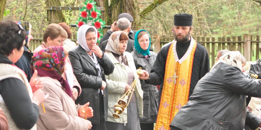 Священник и родственники усопших на кладбище