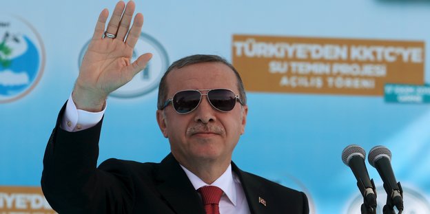 Herr Erdoğan im Anzug mit Sonnenbrille und erhobener Hand