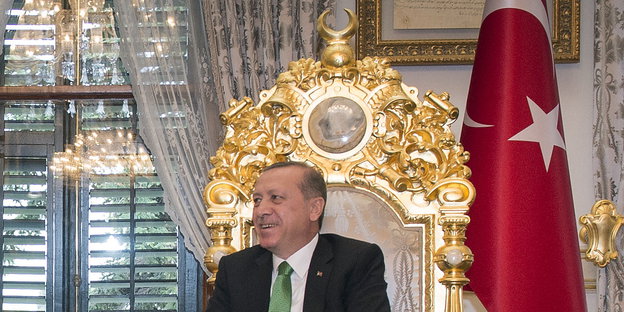 ein Mann auf einem goldenen Thron neben einer Türkei-Fahne