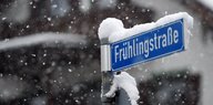 Ein schneebedecktes Straßenschild mit der Aufschrift „Frühlingsstraße“