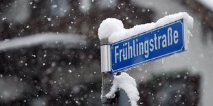 Ein schneebedecktes Straßenschild mit der Aufschrift „Frühlingsstraße“