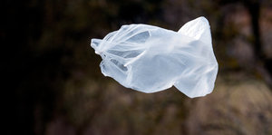 Eine weiße Plastiktüte fligt durch eine dunkle Landschaft