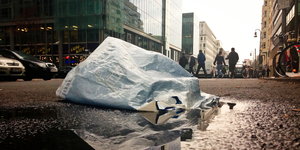 Eine Plastiktüte liegt auf einer nassen Straße in Berlin