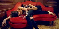 ein Mann und eine Frau liegen auf einem roten Sofa