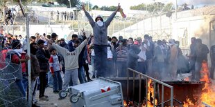 Eine Gruppe vermummter Protestierende neben einem kleinen Freuer