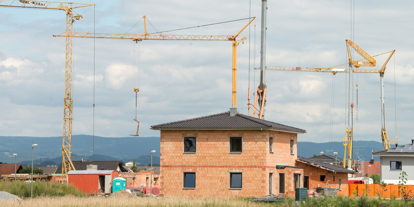 Haus im Rohbau, im Hintergrund Baukräne