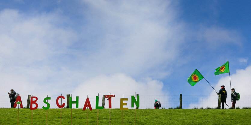 Auf grüner Wiese vor blauem Himmel steht in buten Buchstaben „Abschalten“