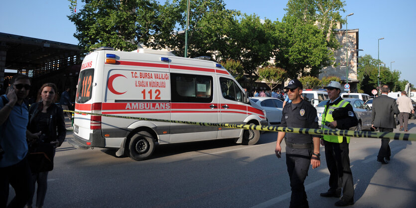 Polizisten und ein Krankenwagen hinter einem Absperrband