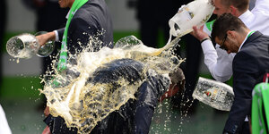 Wolfsburgs Fußballtrainer Dieter Hecking wird von seinen Spieler mit Bier überschüttet