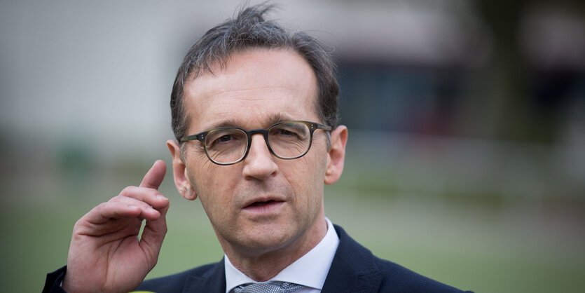 Porträt Heiko Maas, der eine hand an sein rechtes Ohr legt