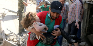 Helfer und Kind zwischen Trümmern in Aleppo