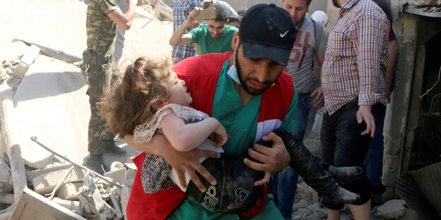 Helfer und Kind zwischen Trümmern in Aleppo