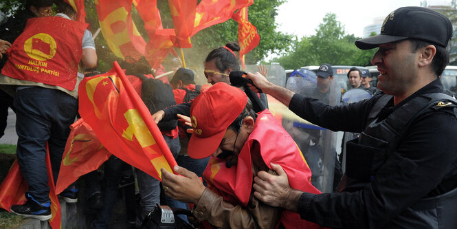 ein Polizist sprüht mit einer Dose Pfeffergas auf Demonstranten