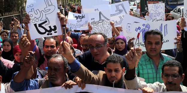 Menschen halten Schilder mit arabischen Schriftzügen und Stifte in die Höhe