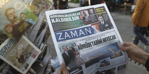 An einem Zeitungsstand hält ein Mensch die Zeitung „Zaman“ in den Händen