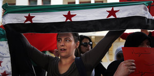 Eine Frau hält die Fahne der syrischen Revolution hoch