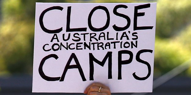 Ein weißes Schild mit der Aufschrift "Close Australia's concentration camps".
