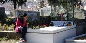 Eine Frau sitzt an einem weißen Grabstein