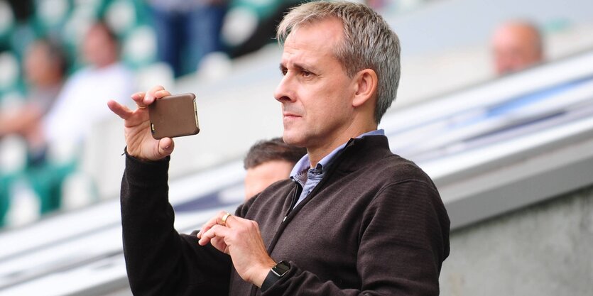 Ein Mann, Pierre Littbarski, fotografiert mit dem Handy