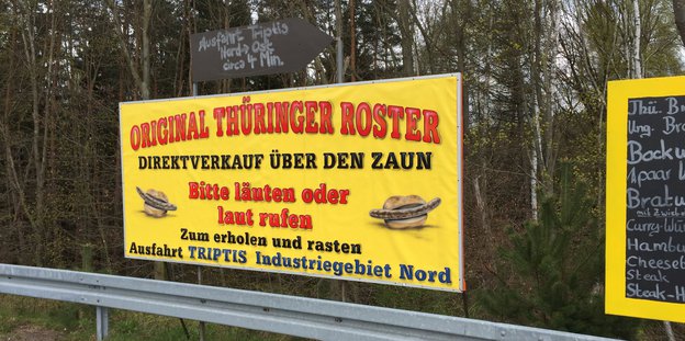 Ein gelbes Plakat mit der Aufschrift "Original Thüringer Roster - Direktverkauf über den Zaun - Bitte läuten oder laut rufen"
