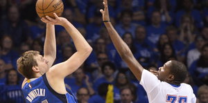 Dirk Nowitzki wirft einen Basketball, ein Gegenspieler der Oklahoma City Thunder versucht, den Wurf zu blocken.
