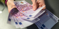 Hände halten mehrere 500-Euro-Scheine in der Hand