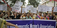Demonstrierende Frauen stehen hinter einem banner