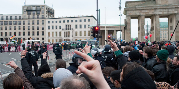 Zwei Demonstrationsgruppen stehen sich am Brandenburger Tor gegenüber, getrennt von Gittern und Polizei