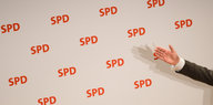 ein Arm vor einer mit SPD-Logos bedruckten Wand