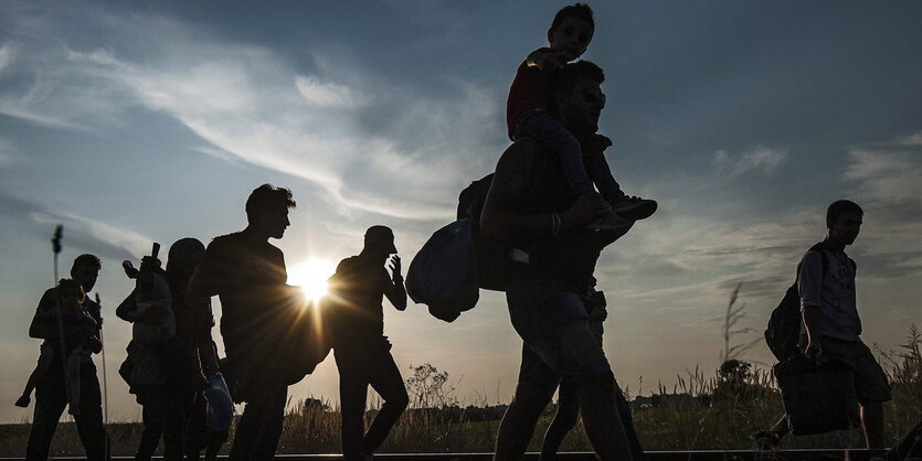 Umrisse einer Menschengruppe, die entlang von Zug-Schienen geht