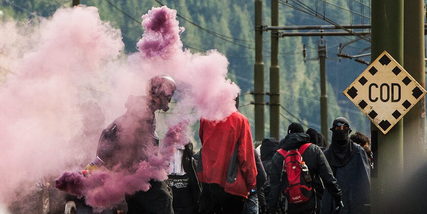 Rauch, Motorradhelm und Taucherbrille. Demonstrant_innen laufen am Brenner