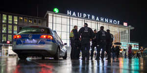 Polizisten und ein Polizeiauto stehen vor dem Kölner Hauptbahnhof
