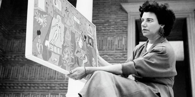 Peggy Guggenheim betrachtet ein Gemälde, das sie in beiden Händen hält