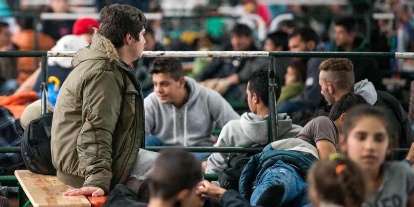 Menschen sitzen auf Bänken in einer Halle