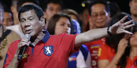 Rodrigo Duterte hält ein Mikrofon in der einen Hand, den anderen Arm weit ausgestreckt