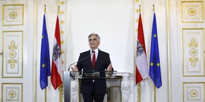 Faymann am Rednerpult vor Österreich- und EU-Flaggen
