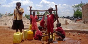 Kinder stehen an einer Wasserstation in Kampala