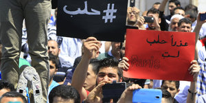 Männer halten Schilder mit arabischen Schriftzeichen in die Höhe