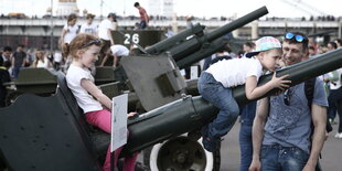 Zwei Kinder sitzen auf dem Zielroher eines Panzers