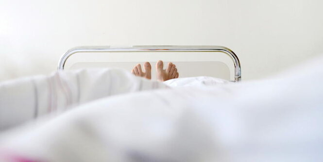 Füße schauen aus einem Krankenhausbett hervor