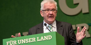 Kretschmann an einem Rednerpult, an dem „Für unser Land“ steht