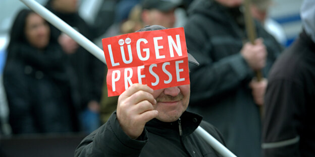Ein Mann auf einer Demonstration mit einem Schild, auf dem „Lügenpresse“ Steht