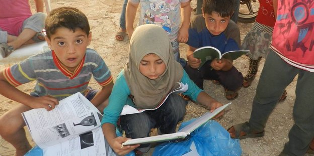 Kinder in einem Flüchtlingscamp lesen Bücher