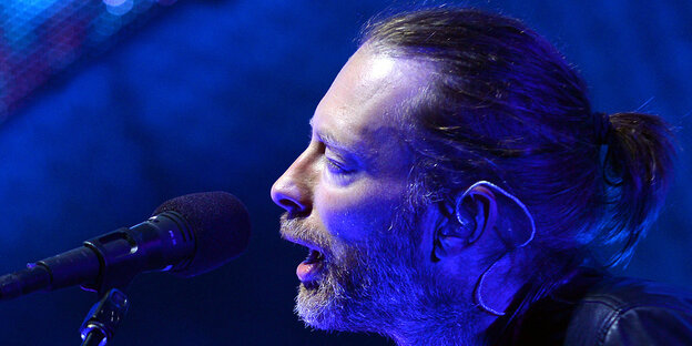 Thom Yorkein am Mikrofon in blaues Licht getaucht