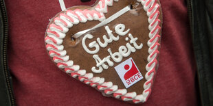 Ein Demonstrant trägt ein Lebkuchenherz mit der Aufschrift: Gute Arbeit