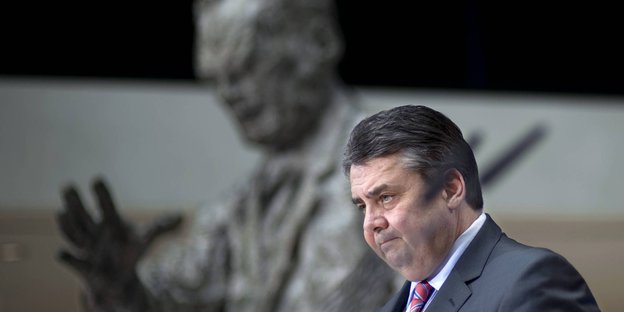 Im Vordergrund Sigmar Gabriel, verschwommen im Hintergrund eine Statue von Willy Brandt
