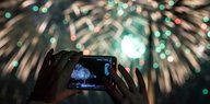 Jemand fotografiert mit seinem Smartphone ein Feuerwerk