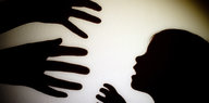 Schatten an der Wand: Zwei Hände greifen nach einem Kind
